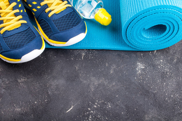 Yoga mat, sport shoes and bottle of water on dark background. Concept healthy lifestyle, sport and diet. Sport equipment - Φωτογραφία, εικόνα