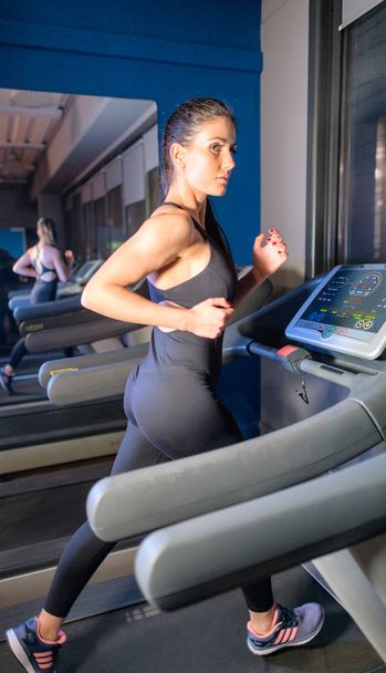 Mujer joven en ropa deportiva corriendo en la cinta de correr en el gimnasio
 - Foto, imagen