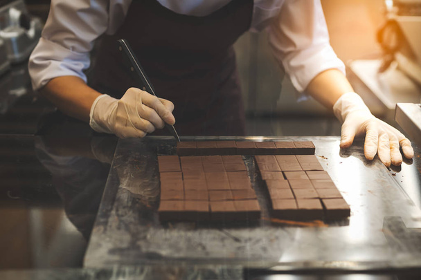 Koch schneidet hausgemachte Schokolade in Küche.  - Foto, Bild