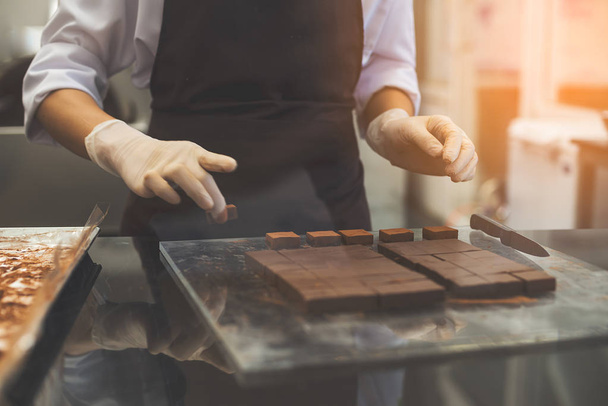 Chef cutting homemade chocolate in kitchen.  - Фото, зображення