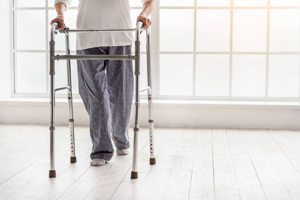 Old woman holding foldable walker and moving in hospital - Photo, Image