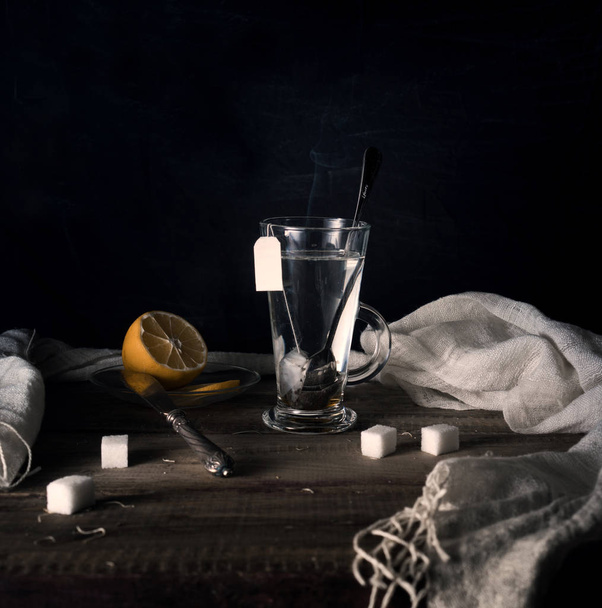 rustic still life. Tea with lemon in a large circle on the wooden table. black background - Fotó, kép