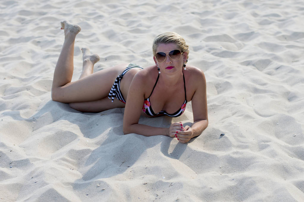 красива жінка лежить на пляжному піску
 - Фото, зображення