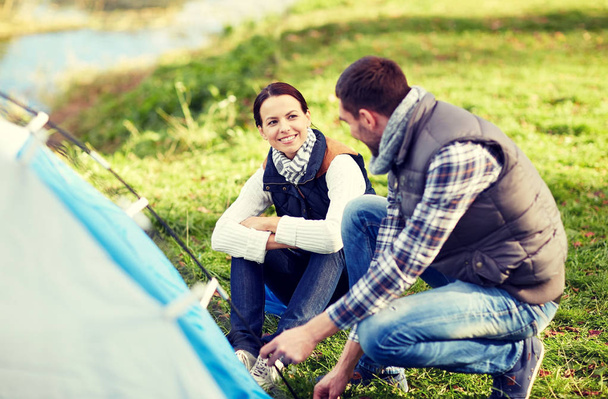 happy couple setting up tent outdoors - Zdjęcie, obraz