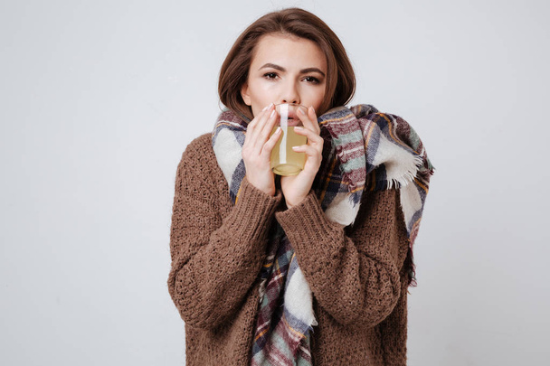 Sick young lady in sweater holding glass with medicine - Foto, afbeelding
