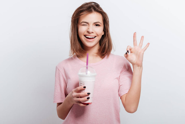 Woman holding cocktail in hands and make okay gesture. - Photo, image
