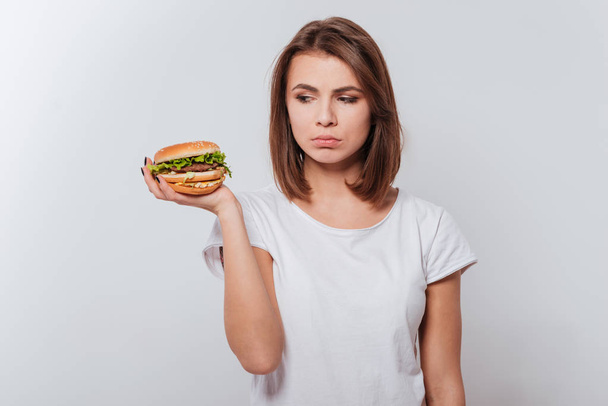 Confused young lady holding fastfood - Valokuva, kuva