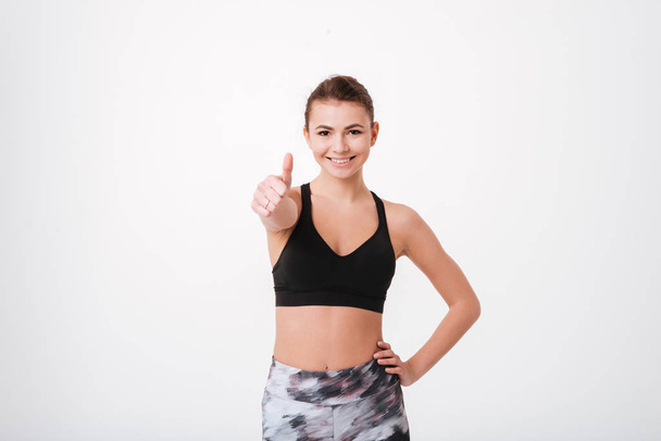 Attractive young fitness lady make thumbs up gesture - Foto, imagen