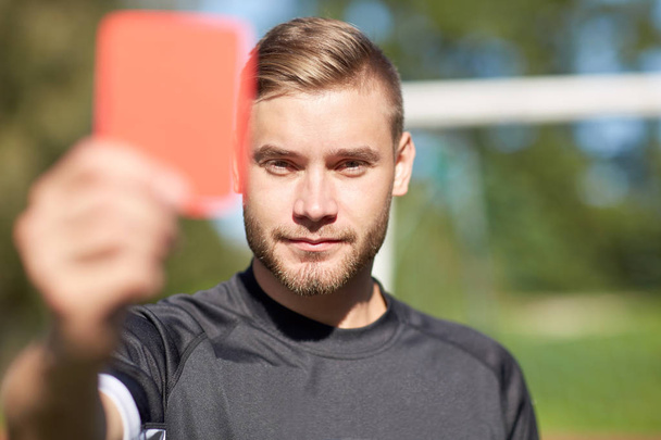 referee on football field showing red card - Foto, afbeelding