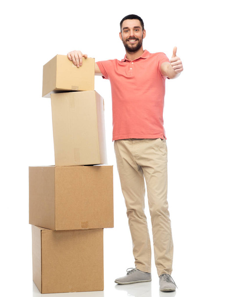 happy man with cardboard boxes showing thumbs up - Fotografie, Obrázek