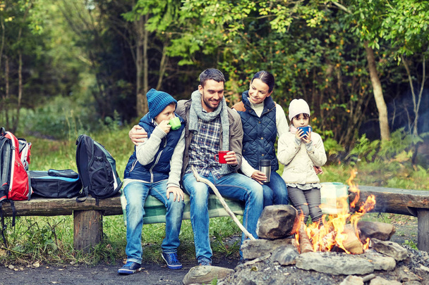 happy family sitting on bench at camp fire - Fotoğraf, Görsel