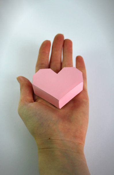 female hand holding a pink heart with voluminous paper on a white background.Valentine's Day - Valokuva, kuva