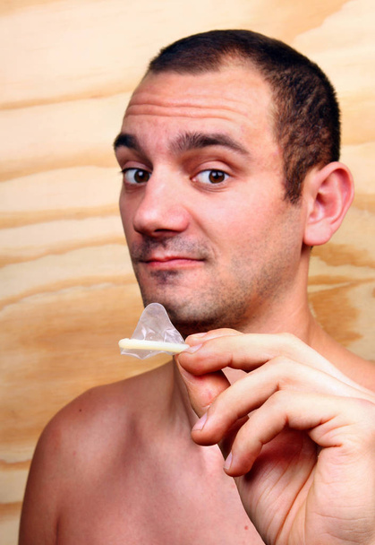 Young handsome boy shows and keeps a condom - Photo, Image