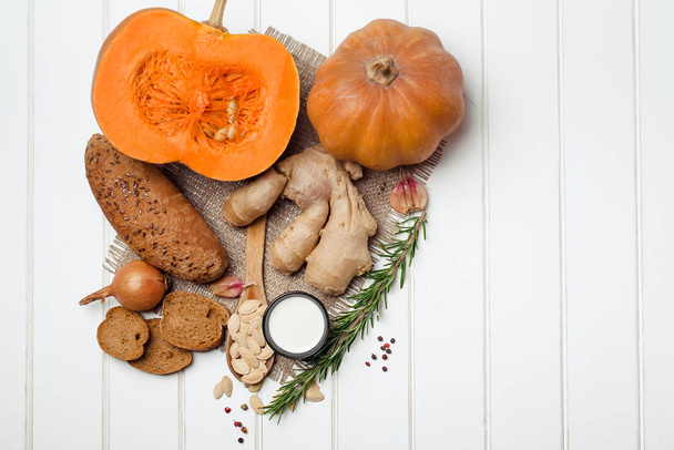 Pumpkin and ingredients for cooking over white wooden background. Vegetarian food, health or cooking concept. - Fotografie, Obrázek