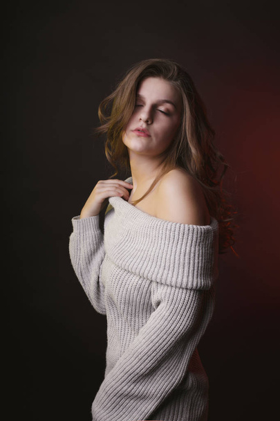 Sensual young woman posing in sweater with naked shoulders - Fotoğraf, Görsel