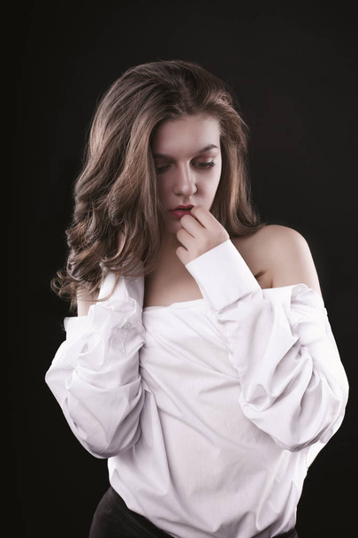 Tender young lady posing in men's shirt at studio - Zdjęcie, obraz