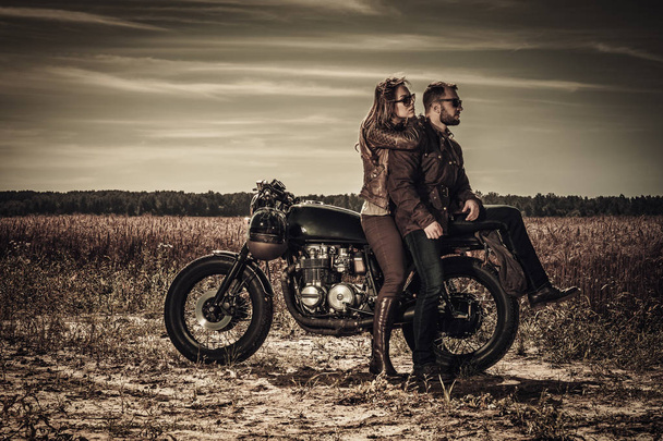 Young, stylish cafe racer couple on vintage custom motorcycles in field - Photo, Image