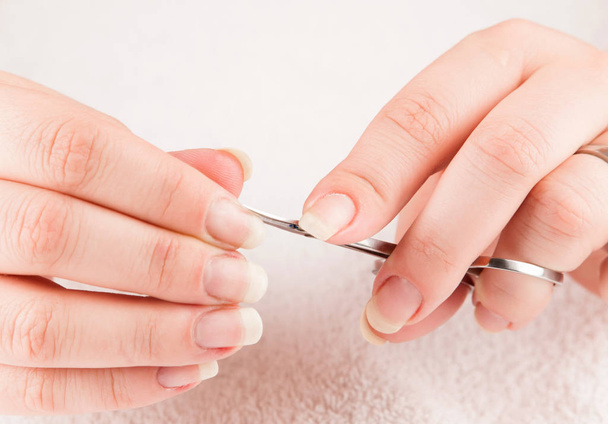 Vrouw maken van manicure zelf, met behulp van schaar - Foto, afbeelding