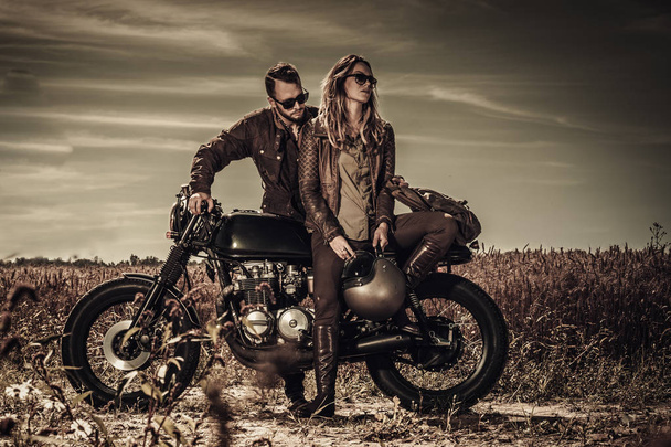 Jeune, élégant couple de coureur de café sur les motos personnalisées vintage dans le domaine
 - Photo, image