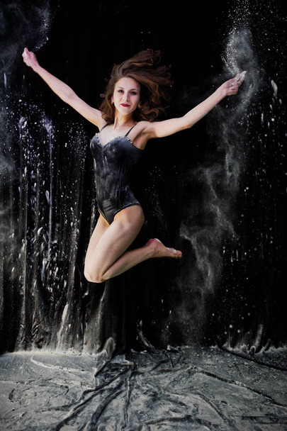 Дівчина танцює стрибає і танцює в білому пилу з борошном на
  - Фото, зображення