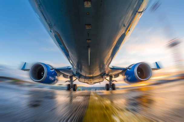 Самолет в движении во время взлета и посадки, на фоне заката и мокрой взлетно-посадочной полосы
 - Фото, изображение