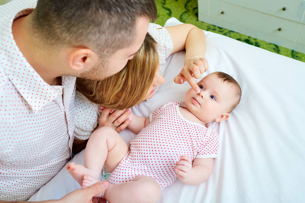 Baby with his mother and father on the bed playing together. Hap - Zdjęcie, obraz