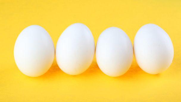 Eggs isolated on yellow background - Foto, imagen