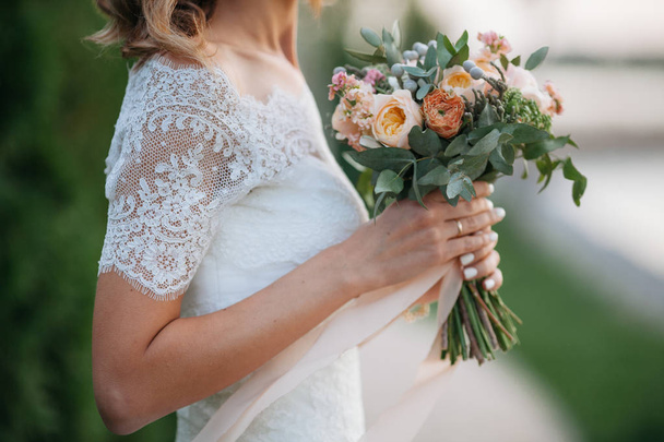 Wedding. The bride in a dress standing in a green garden and hol - Φωτογραφία, εικόνα