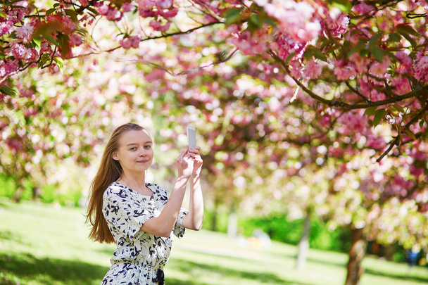 Beautiful young woman in blooming spring park - Valokuva, kuva