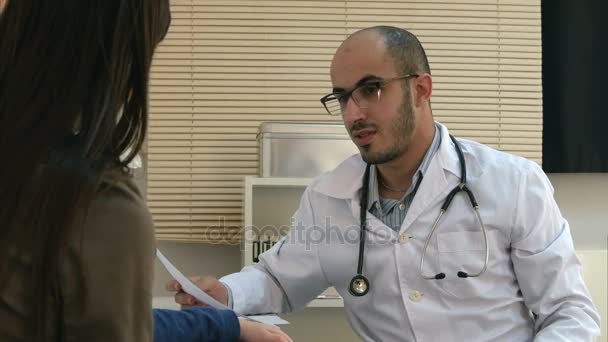 Young doctor in glasses explaining diagnosis to mother and her child - Πλάνα, βίντεο