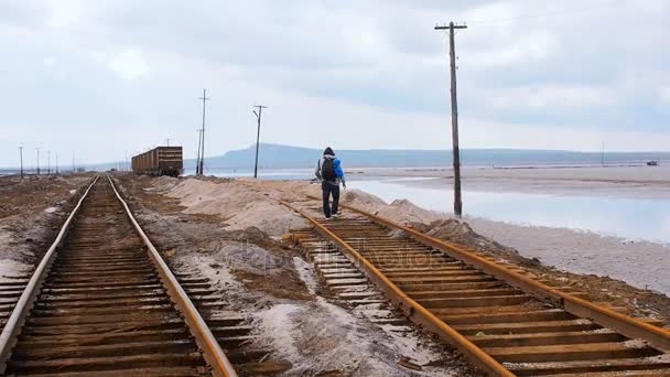 男は、鉄道で行きます。古いワゴンにクロスの関係上を歩いて観光。塩の湖を古いさびた鉄道。生理食塩水の塩の湖 Baskunchak ロシア - 映像、動画