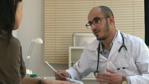 Arabian male doctor explaining cardiogram to female patient - Materiaali, video