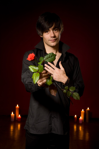 Young man with rose in black shirt on red backg - Fotografie, Obrázek