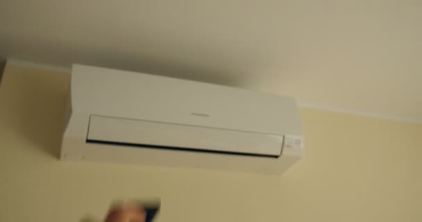 El hombre encendió un moderno dispositivo de aire acondicionado desde el mando a distancia seleccionando el aire acondicionado del hotel durante el invierno y el aire frío durante el verano. - Metraje, vídeo