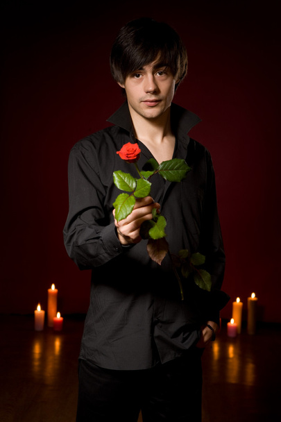 Young man with rose in black shirt on red backg - Zdjęcie, obraz