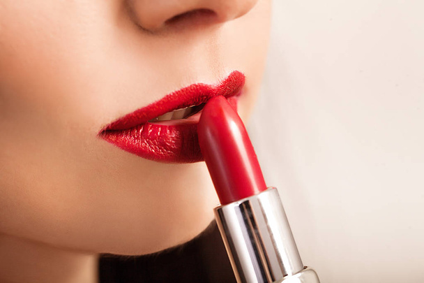 Beautiful woman paints lips with lipstick. Beautiful woman face. Makeup detail. Beauty girl with perfect skin - Photo, Image