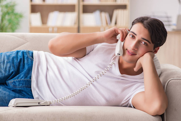 Νεαρός άνδρας μιλάει στο τηλέφωνο ξαπλωμένη στο καναπέ - Φωτογραφία, εικόνα