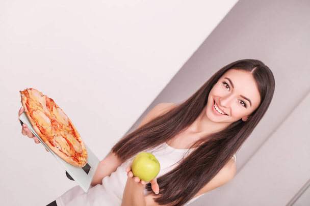 Diet. Young beautiful woman makes a choice between healthy lifestyle and harmful food. The concept of healthy eating and obesity. Beautiful slender figure girl - Φωτογραφία, εικόνα