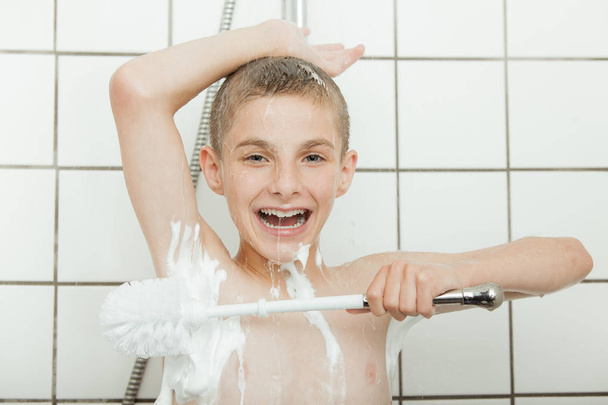 Joven chico duchándose usando cepillo grande
 - Foto, imagen