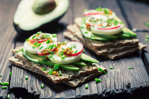 Tasty sandwich with avocado, eggs and radish - Foto, afbeelding