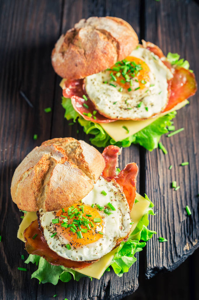 Delicious burger with lettuce, bacon and eggs - Foto, afbeelding