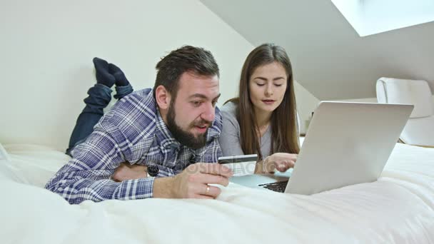 glückliches Paar mit einem Laptop, der zu Hause auf dem Bett liegt - Filmmaterial, Video
