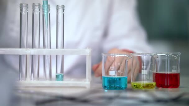 De wetenschapper werken met vloeistof in laboratoriumglaswerk. Reageerbuisjes vloeistof te vullen - Video
