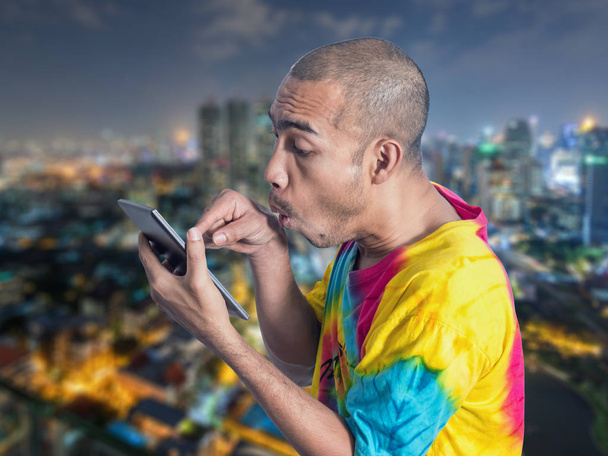 Asian man holding digital tablet with overacting on defocus city - Photo, Image