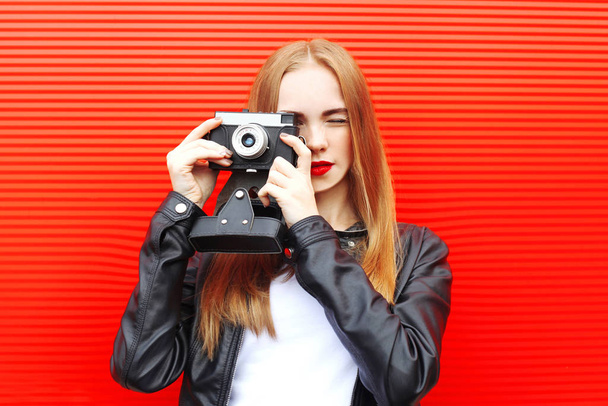 Fashion pretty woman with vintage camera in city over red backgr - Foto, Bild