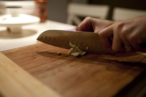 Hand cutting garlic on wooden worktop - Photo, Image