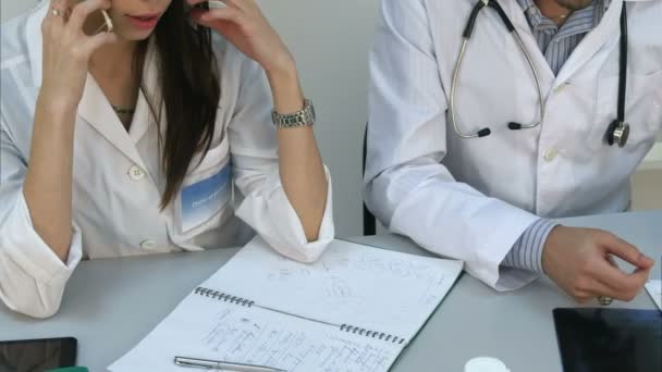 Asistente femenina hablando por teléfono pidiendo consejo al médico masculino
 - Imágenes, Vídeo