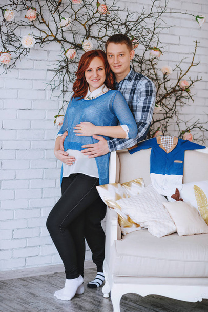 Una joven pareja embarazada enamorada de pie cerca. El marido abraza a su esposa. Con colores de cuarzo rosa y azul cielo
. - Foto, imagen