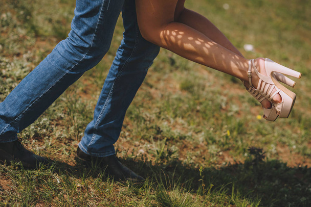 Legs feet couples in love. He turns her in his arms, on the green grass near the sea. - Photo, Image