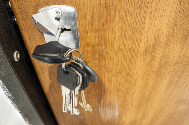 Close-up de pacote de chaves diferentes no buraco da chave em textu de madeira
 - Foto, Imagem